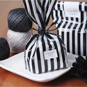 Square THANK YOU seal stickers on black and white striped gift bags for elegant packaging