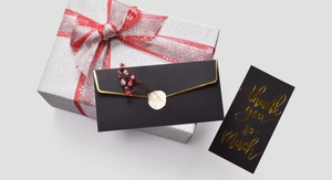 Detail of a black gift envelope with gold foil lettering, wax seal, and dried flowers