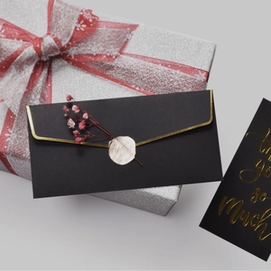 Elegant black gift envelope with gold foil edges and pink dried flowers with wax seal