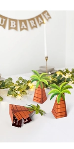 Macro shot of palm tree shaped candy boxes with green leaves on a festive white table