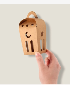 Geschenkbox aus braunem Kraftpapier mit Stern- und Mond-Ausschnitten in der Hand