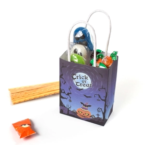 Purple Halloween Trick or Treat paper gift bag filled with various festive candies