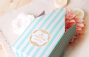 Macro detail of Tiffany blue striped gift box with gold logo on soft fabric background