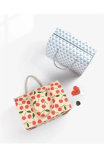 Detail of paper gift bags with cherry and floral prints featuring woven rope handles