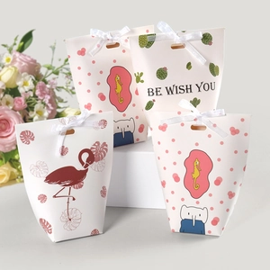 Detail of four candy gift boxes with flamingo and cactus prints plus white ribbon bows