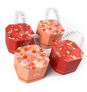 Dettaglio di scatole per confetti ottagonali rosse e rosa con motivi floreali dorati