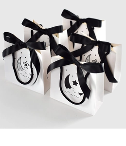 Close-up of white star and moon paper gift bags with large black satin bow handles