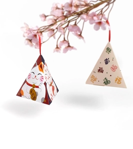 Detail of triangle pyramid gift box with Maneki-Neko design and red ribbon handle