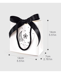 Detailed view of small white gift bag with black ribbon bow and moon star illustration