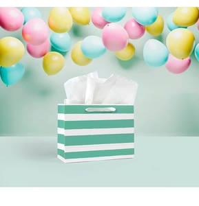 Detail of mint green striped gift bag with satin handles and party balloon background