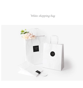 Detailed view of white kraft paper bags with twisted handles and black Thank You stickers