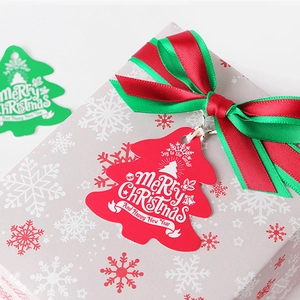 Christmas tree gift tags in red and green colors on a holiday gift box with red ribbon