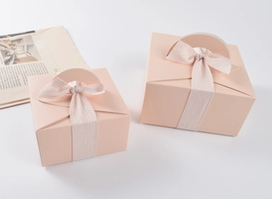 Dettaglio di scatole regalo quadrate rosa con manici curvi e fiocchi di nastro