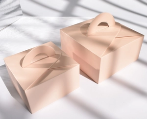 Dettaglio di scatole per torta quadrate rosa opaco in due dimensioni con manici integrati