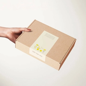 Geschenkbox aus Kraftpapier mit Blumenaufkleber 'Just for You' in den Händen