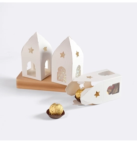 Gros plan de boîtes cadeaux blanches ajourées avec fenêtres étoilées et chocolat