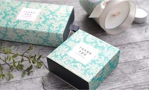 Detail der tiffanyblauen Geschenkbox mit Damastmuster und grauem Seidenbandgriff