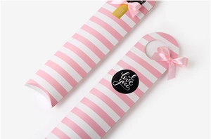 Close-up of pink striped rectangular gift box featuring a satin bow and for you tag