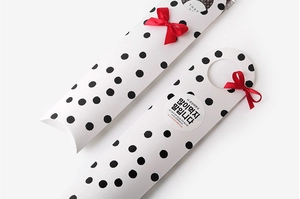 Close-up of long cookie gift box with black polka dots and a red satin ribbon bow