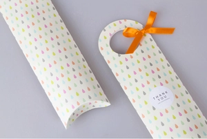 Detalle de cajas de regalo blancas con patrones de lluvia coloridos y cintas naranjas