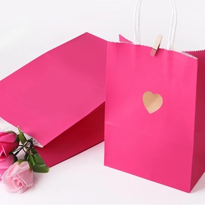 Rose pink gift paper bags with white twisted handles and gold heart sticker