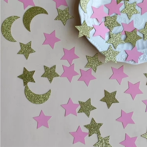 Close-up of gold glitter stars and moon confetti with pink paper stars for party decor