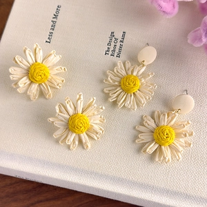 Handmade summer daisy earrings with white petals and yellow centers in a flat lay view