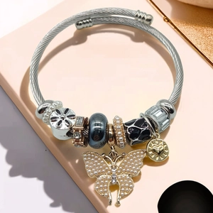 Detailed view of beaded bracelet featuring a pearl butterfly charm and gold heart pendant
