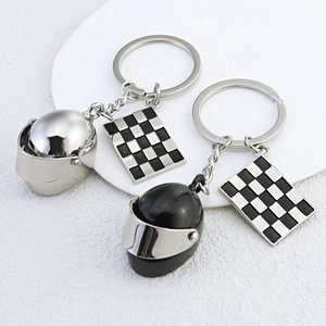 Racing keychain with metallic motorcycle helmet and checkered flag charms on white plate