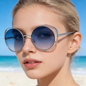 Detail of silver dual-frame round sunglasses with blue gradient lenses on a beach model