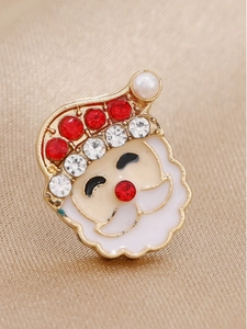 Vue macro d'une broche Père Noël avec strass rouges brillants et détails en émail