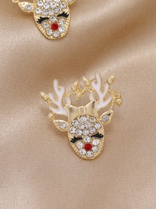 Détail de boucles d'oreilles renne de Noël dorées avec strass brillants et émail blanc
