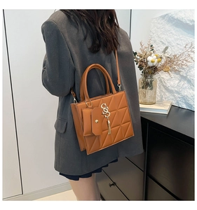 Dettaglio della borsa trapuntata marrone con logo S in metallo e pendente con frange