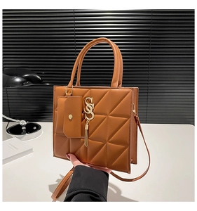 Dettaglio della borsa tote trapuntata marrone con ciondolo logo dorato e mini pochette