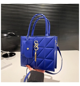 Dettaglio della borsa trapuntata blu acceso con logo S dorato e mini portamonete