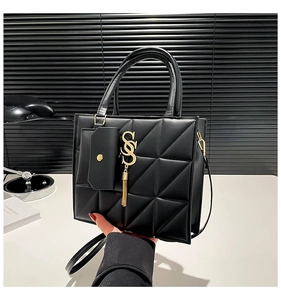 Dettaglio borsa tote nera trapuntata con ciondolo SS dorato e tracolla rimovibile