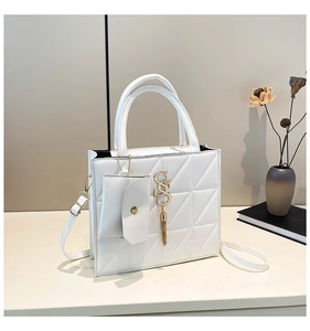 Dettaglio di borsa tote in pelle bianca trapuntata con logo dorato e nappa