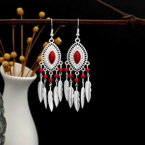 Macro detail of Bohemian silver earrings with red stone and hanging metal feathers