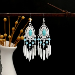 Detailed shot of bohemian tassel earrings with turquoise and feathers on a branch