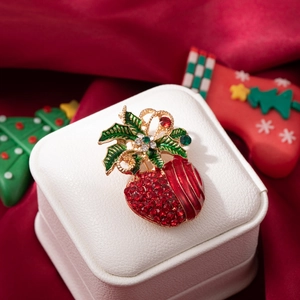 Sparkly Christmas berry brooch with red crystals and gold bow on a gift box background