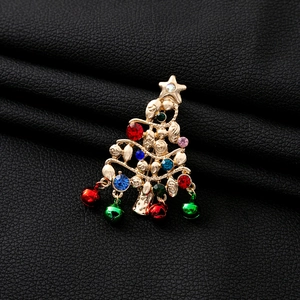Detail of Christmas tree brooch with colorful rhinestones and hanging bells on leather