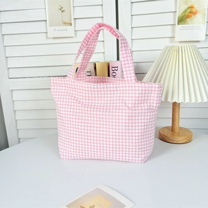 Detailed view of pink and white checkered canvas tote bag in a cozy lifestyle setting