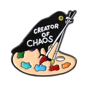 Black raven crow enamel pin on color palette with Creator of Chaos text engraving
