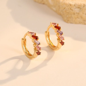 Close-up of gold hoop earrings with colorful baguette-cut pink and purple zircons