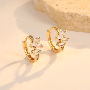 Detail of gold huggie hoop earrings with rectangular and round cubic zirconia stones