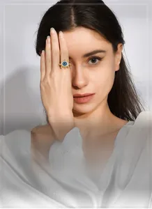 Detail of gold-plated wheat ear ring with blue stone and zircon inlay on finger