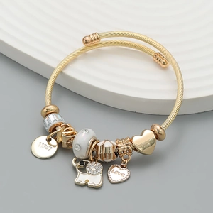 Gold charm bracelet with elephant and heart pendants on elegant grey and white display