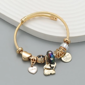Detail of a gold charm bracelet featuring a heart love pendant and a cute bear charm