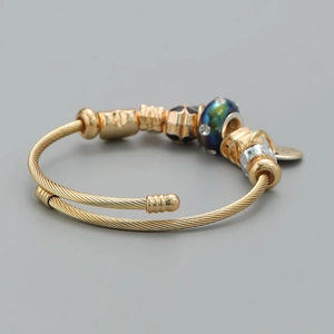 Detailed view of a gold cable bracelet featuring decorative beads and a charm