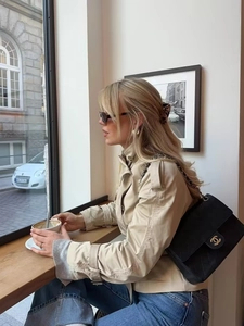 Short beige trench coat with lapel and belt styled with denim and black chain bag